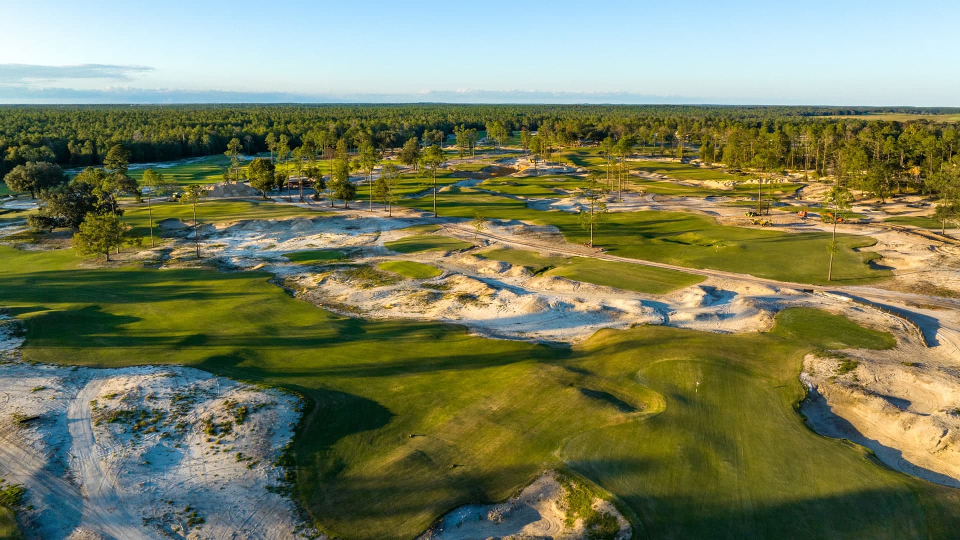 Golden light over the sweeping sand barrens, rolling fairways, and mature trees of Karoo at Cabot Citrus Farms